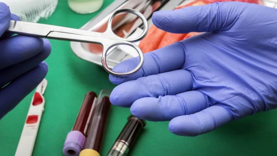 Surgeons hands holding and passing surgical instrument to other doctor while operating patient surgical technologists