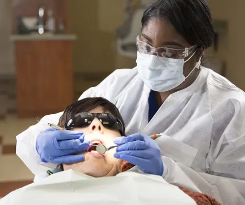 Dental hygienist providing dental care to patient